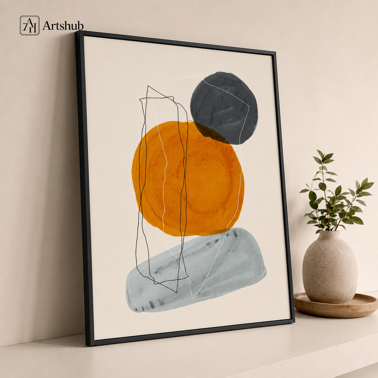 Artshub Art in Harmony Amber Orange Charcoal Abstract Circles single panel framed canvas wall art leaning on cream wall with ceramic vase and green plant on wooden tray — amber orange charcoal grey matte black frame