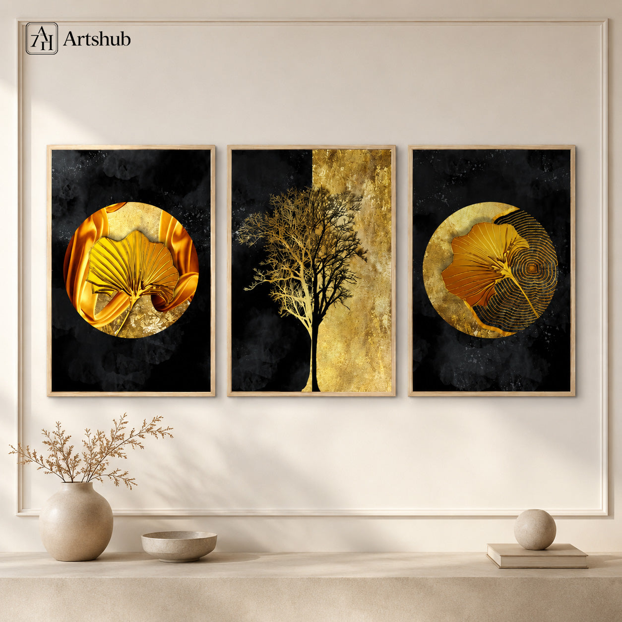 Artshub Golden Orbit 3-panel triptych canvas framed wall art displayed on a cream white wall with large round ceramic vase with dried branches, small ceramic bowl and round ceramic sphere – left panel golden silk ginkgo leaf on gold circle, centre panel bare black tree on gold leaf texture, right panel golden ginkgo with concentric rings, all in natural wood floater frames