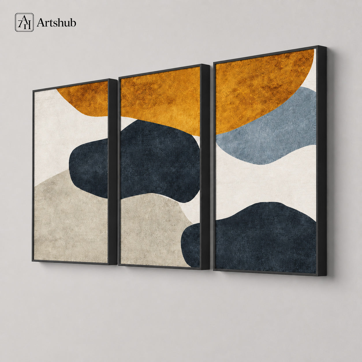 Artshub Amber Stone 3-panel triptych abstract canvas framed wall art – 45 degree three-panel view on light grey wall showing full panoramic composition – left panel amber orange half-circle with cream and navy pebble, centre panel amber orange and deep navy charcoal pebble with sandy beige wave, right panel amber orange with slate blue wave and deep navy shape, all in premium black floater frames with textured canvas surface