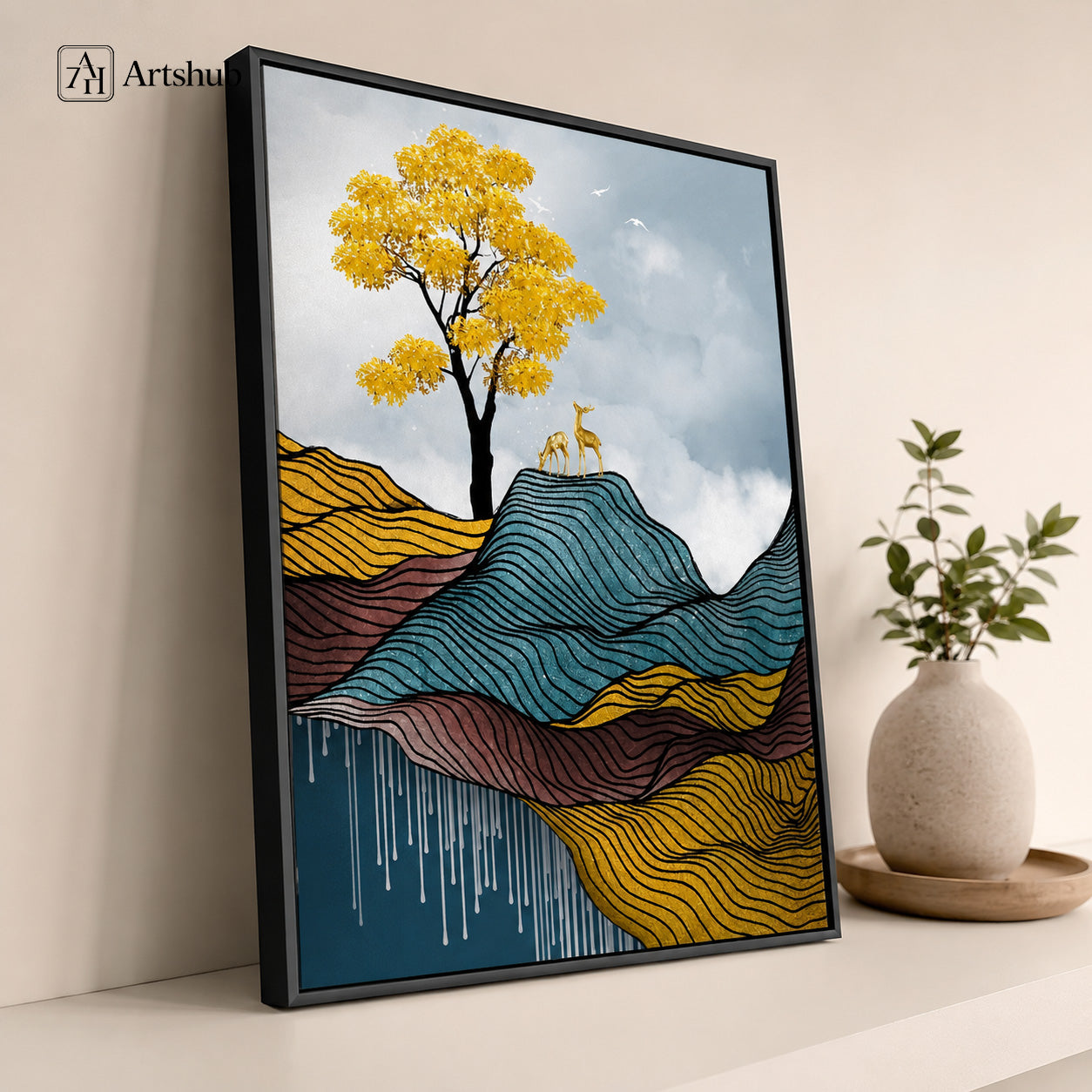 Artshub Golden Stillness Yellow Tree Deer Fine Line Wave Mountain single panel framed canvas wall art leaning on warm cream wall with round ceramic vase and green plant on wooden tray — golden yellow teal burgundy matte black frame