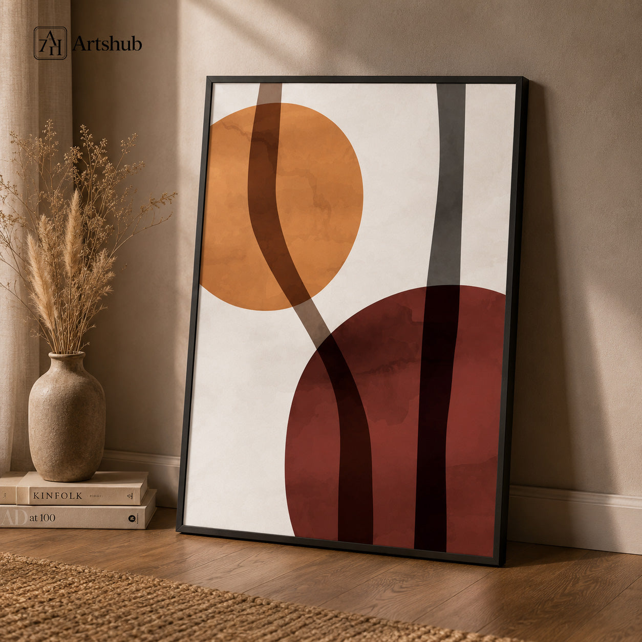 Artshub Art That Elevates Every Space Amber Burgundy Abstract Circles single panel framed canvas wall art leaning on warm beige wall with pampas grass vase and Kinfolk books on floor — amber burgundy charcoal matte black frame