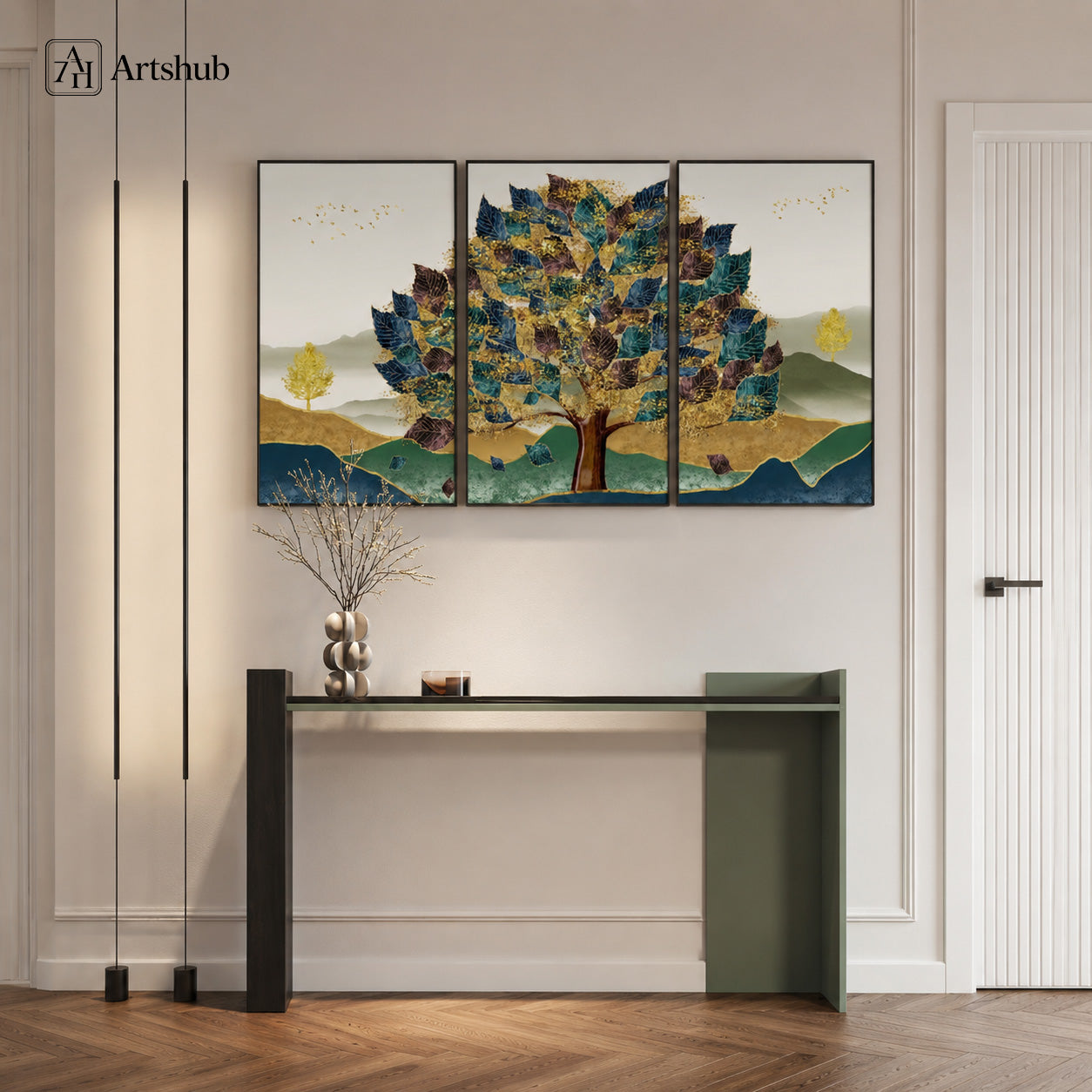 Artshub Golden Canopy 3-panel triptych canvas framed wall art displayed on a white hallway wall above a dark console table with sculptural vase and decorative object, pendant floor lights and herringbone wood floor – majestic tree triptych in teal, navy, gold and dark brown on misty mountain landscape with black floater frame