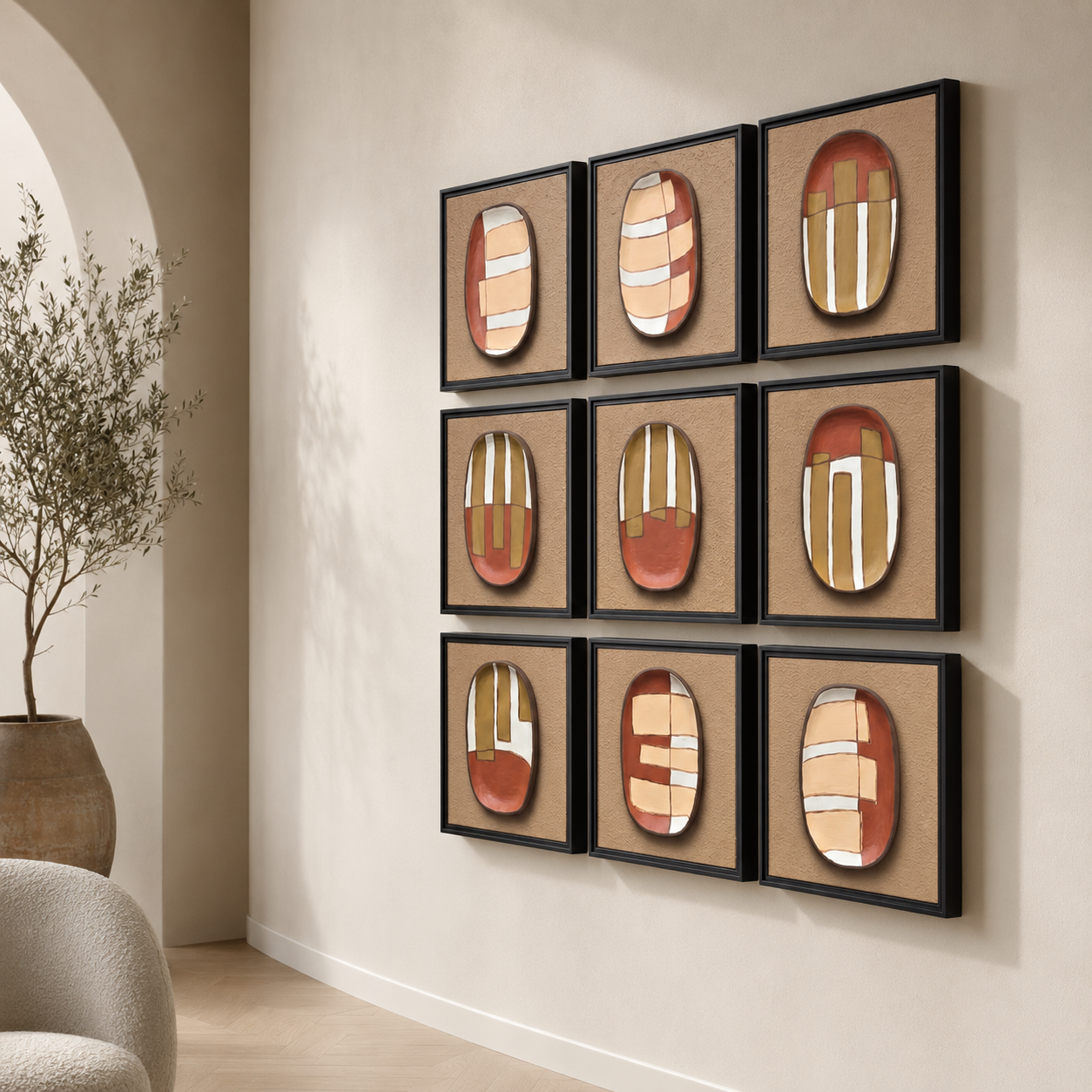 Artshub Ceramic Ovals 9-panel handcrafted abstract 3D ceramic framed wall art set displayed in a 3x3 grid on a cream arched hallway wall with large olive tree in terracotta pot and cream boucle armchair – timeless art modern soul handcrafted elegance